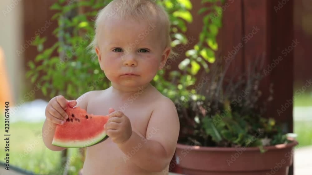 Little sweet baby boy, eating yummy peace of watermelon, dripping and smiling happily Little sweet baby boy, eating yummy peace of watermelon, dripping and smiling happily