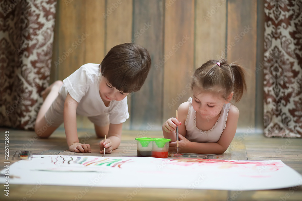 Little children paint on a large sheet of paper Little children paint on a large sheet of paper
