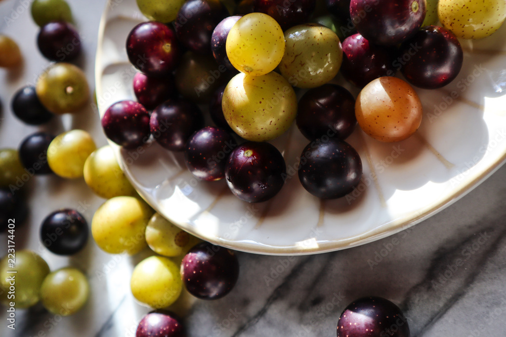 Muscato muscadine sweet green bronze and purple black grape on white marble board Muscato muscadine sweet green bronze and purple black grape on white marble board