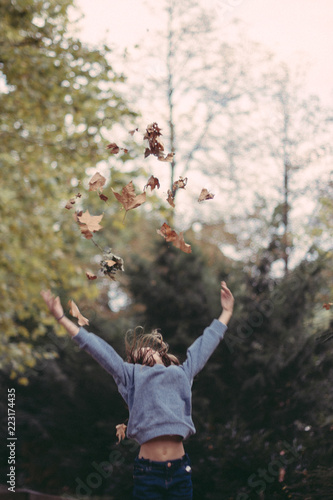 portrait fillette qui joue avec les feuilles mortes en automne