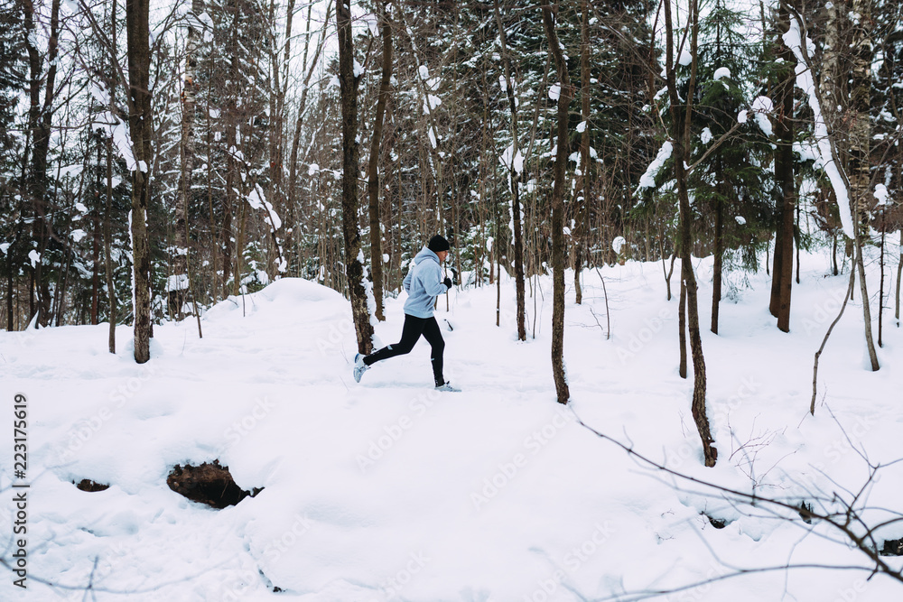 Side view of young sportsman exercising in snow forest