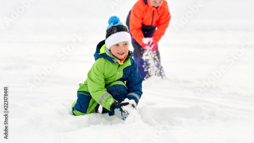 childhood, leisure and season concept - happy little kids in winter clothes playing with snow outdoors © Syda Productions