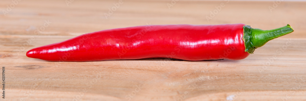 eine rote scharfe Chili auf einem Holzbrett Peperoni eine rote scharfe Chili auf einem Holzbrett Peperoni