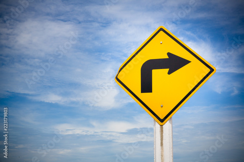 turn right traffic sign on yellow background with cloudy blue sky. symbol for transportation regulations. image for background, wallpaper and backdrop.