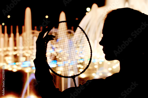 Silhouette of girl with badminton racket in hand.
