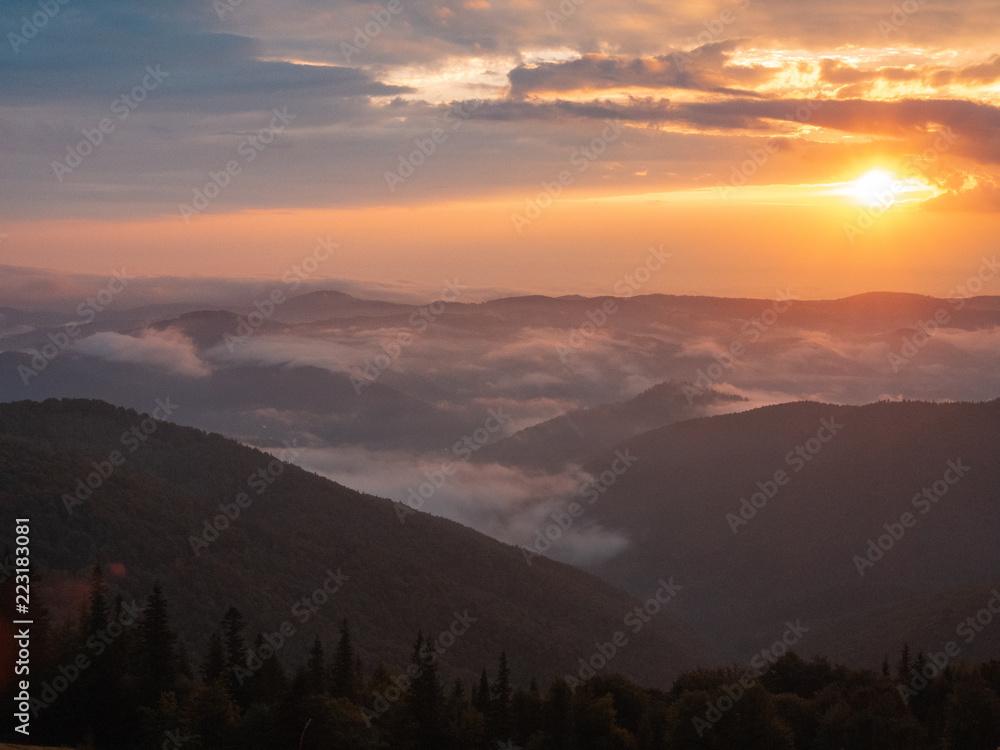 Landscape of Carpathians mountains, west Ukraine. Low clouds flowing round mountains peaks. The sun going west in the evening. Ukrainian nature landscape at summer. Blurred background