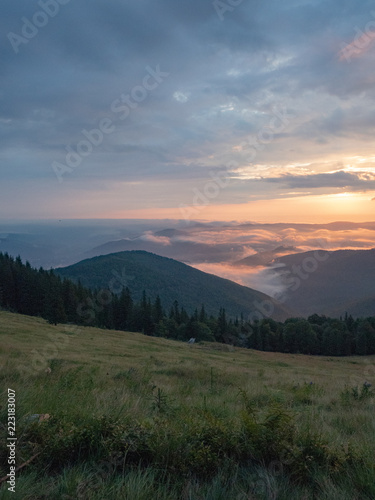 Carpathians landscape in august, west Ukraine. Sundown in mountains at summer. Ukrainian nature background. The sky covered with grey clouds illuminated by the sun. Blurred background