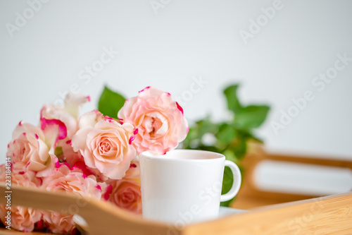 cup of tea with roses on a wooden tray