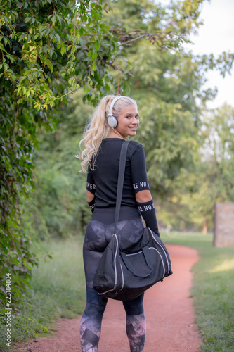 Smiling woman with a sports bag listening to music