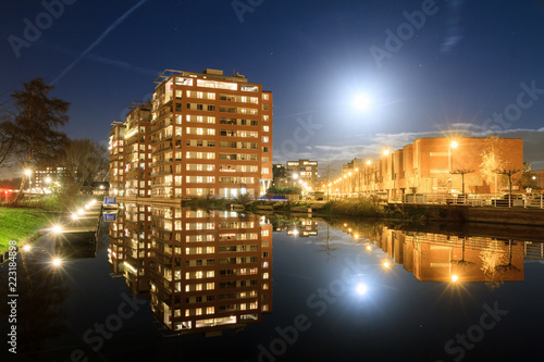 Modern new residential district in Leiden, The Netherlands, with apartment buildings reflected in the water at night, with a full moon

