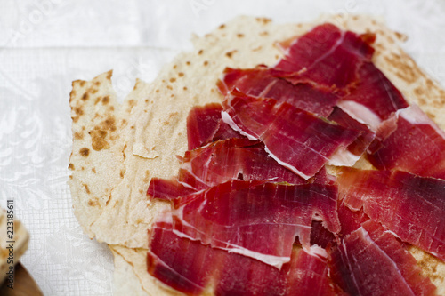 Vassoio di prosciutto tagliato finemente a fette sopra una sfoglia di pane carasau photo