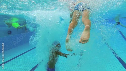 The teenager swims in the pool under the water.