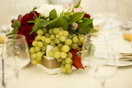 Centro tavola con fiori e uva bianca in tavola bandita a festa photo