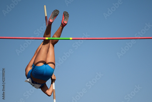 Competition pole vault jumper female on blue sky background