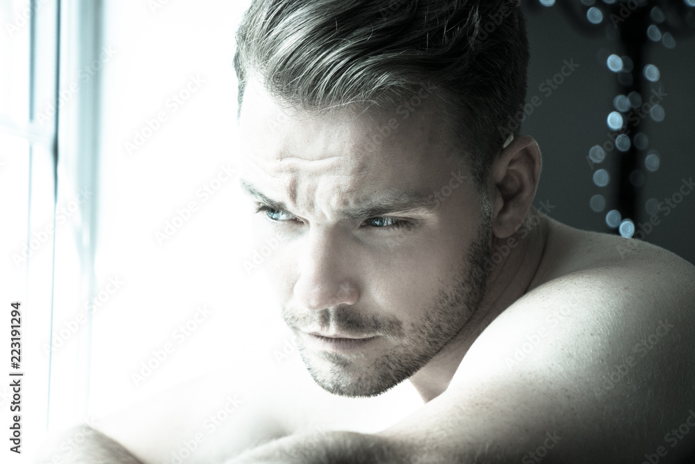 Hunky muscular, sexy shirtless man with defined abs and muscles looks out of window Hunky muscular, sexy shirtless man with defined abs and muscles looks out of window