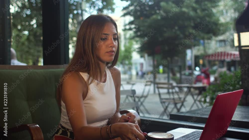 Young attractive freelancer having coffee while working at a coffee shop with a laptop Young attractive freelancer having coffee while working at a coffee shop with a laptop