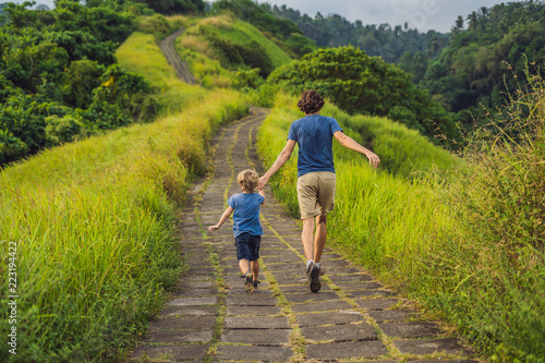 Dad and son tourists in Campuhan Ridge Walk , Scenic Green Valley in Ubud Bali. Traveling with children concept photo