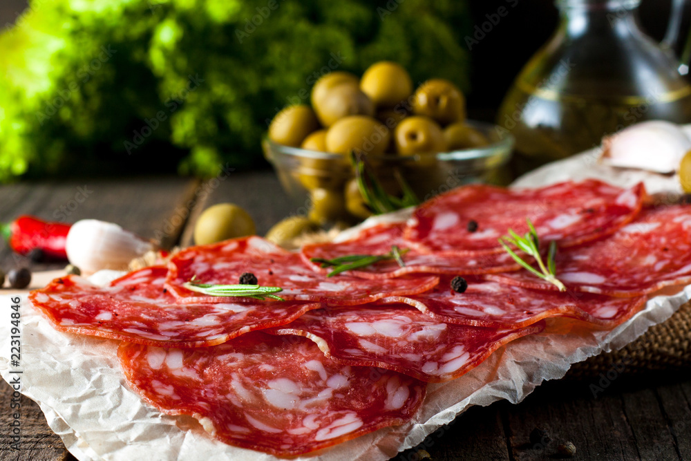 Obraz premium Chorizo sausage and salami, thin cut. spanish salami on the wood background with spices, paprika, pepper. Spicy food. Chili.
