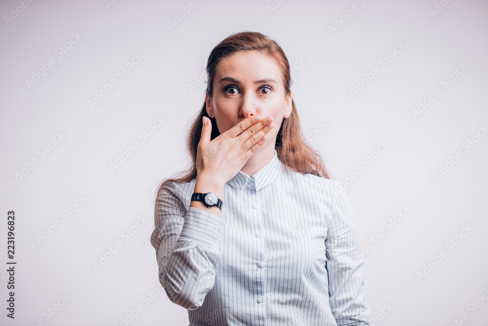 Surprised beautiful business woman on white background. Girl closes her mouth with her hand Surprised beautiful business woman on white background. Girl closes her mouth with her hand