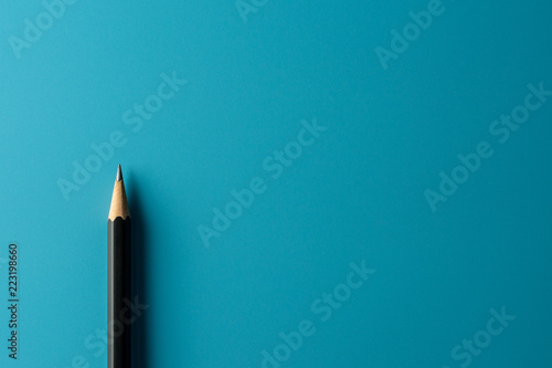 Black pencil on blue paper background. - Business concept. photo