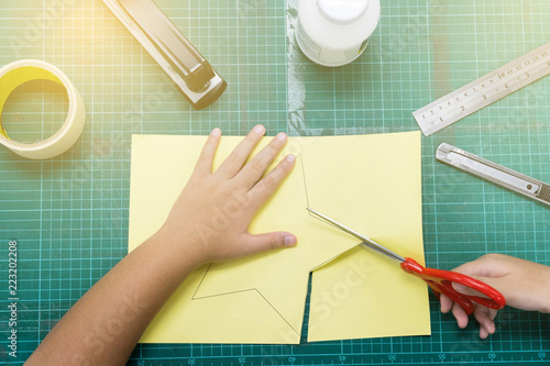 The boys are cutting the paper in a star pattern