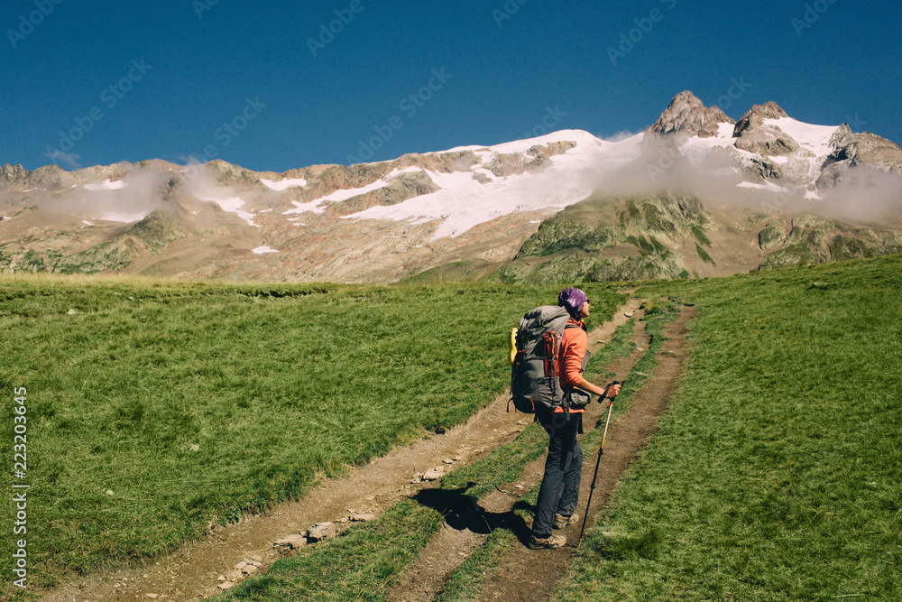 woman with a backpack, hiking with trekking poles in mountain . Hiking around Mont Blanc