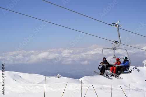 White snow-capped mountain slopes with skiers and a ski lift with skiers 