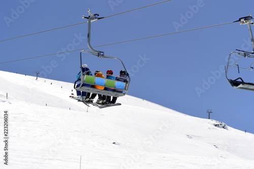 White snow-capped mountain slopes with skiers and a ski lift with skiers 