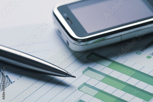 Mobile Phone And Pen On Financial Graphs Close-up