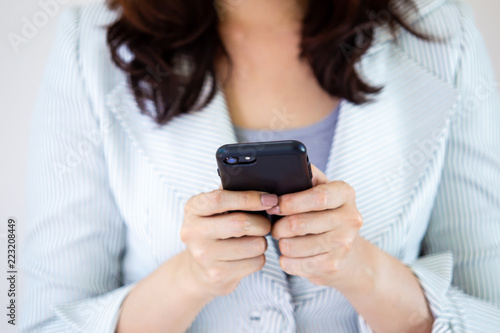 Asian business women in the white suit are using a smartphone.