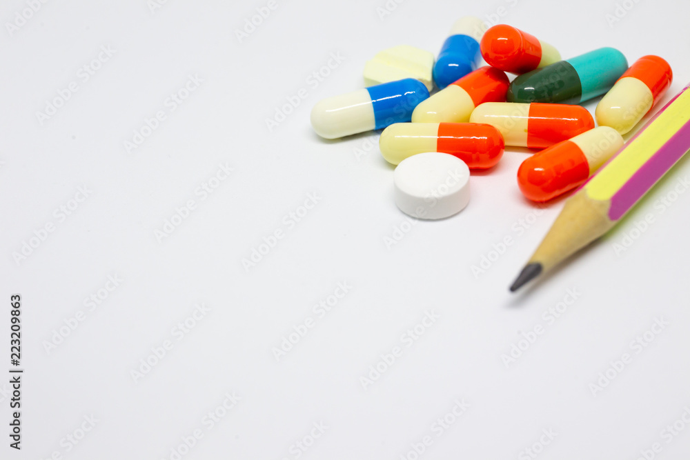Pills and capsules on white background with a pencil, concept of medical and health care. Pills and capsules on white background with a pencil, concept of medical and health care.