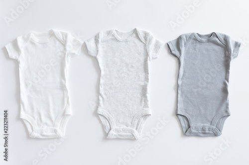 Set of unisex clothing and accessories for a baby in neutral colors, top view and flat lay on white background