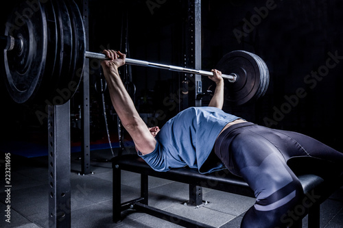 Athletic Man In Gym Exercising On The Barbell Bench Press.