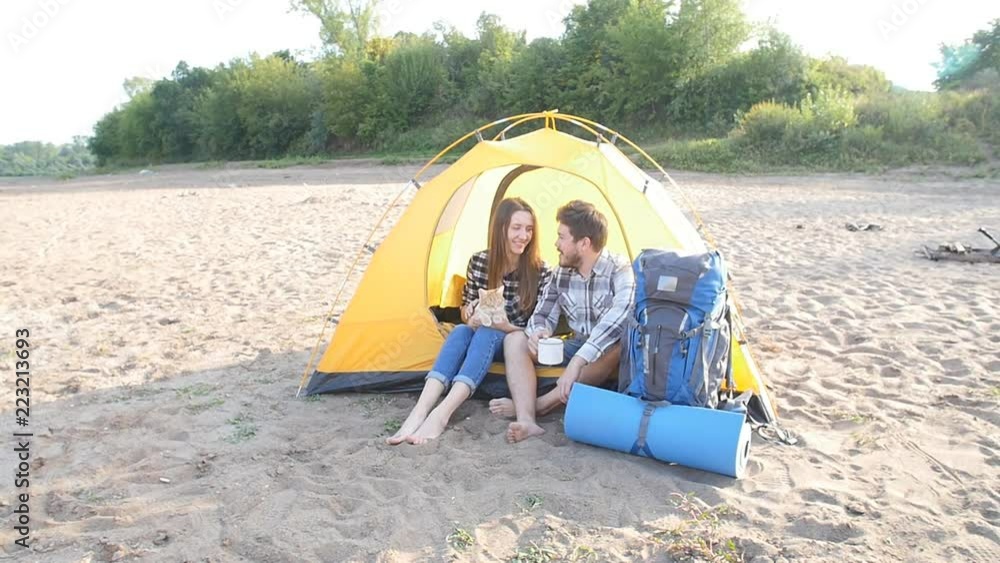 Concept of tourism and travel. Young happy couple sitting in tent watching the view Concept of tourism and travel. Young happy couple sitting in tent watching the view