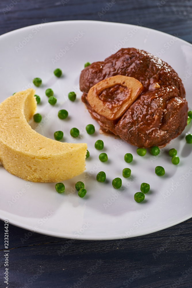 Unusual serving of food in a cafe, restaurant. Potato puree / polenta in the form of an incomplete moon, green peas in the form of stars in the sky. A large piece of appetizing meat on the bone. Unusual serving of food in a cafe, restaurant. Potato puree / polenta in the form of an incomplete moon, green peas in the form of stars in the sky. A large piece of appetizing meat on the bone.