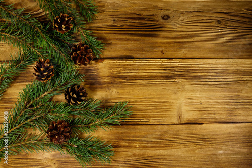 Christmas composition with fir tree branches and cones on wooden background. Top view, copy space