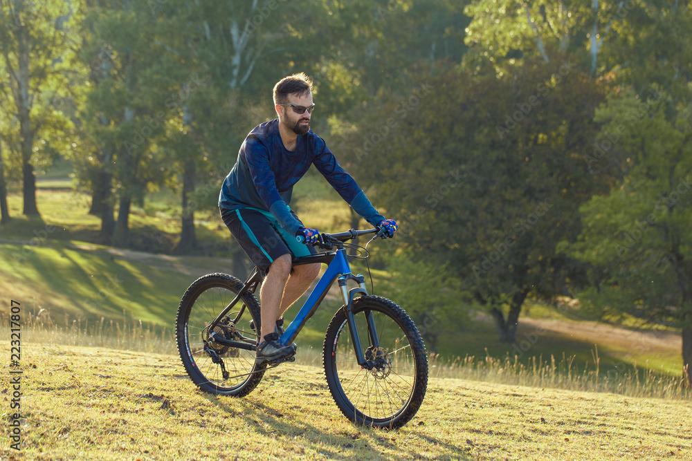 Fototapeta premium A cyclist rides the hills, Beautiful portrait of a guy on a blue bicycle