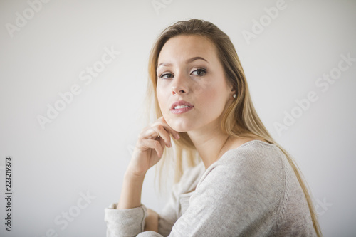 Frau sitzt vor einer weißen Wand