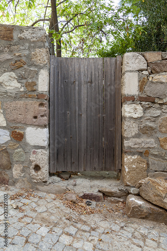 Old wooden garden door on slope into garden with stone walls at Tenedos (Bozcaada) Island by the Aegean Sea