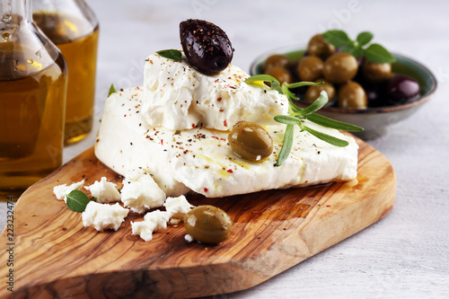 Greek cheese feta with herbs and olives on rustic table.
