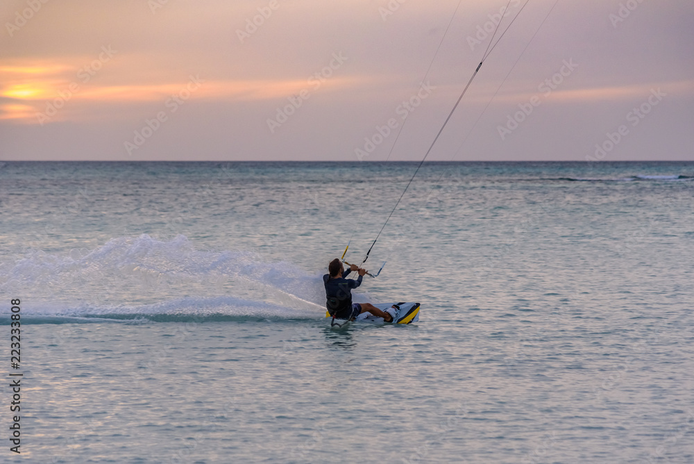 Naklejka premium A man does acrobatics while kitesurfing
