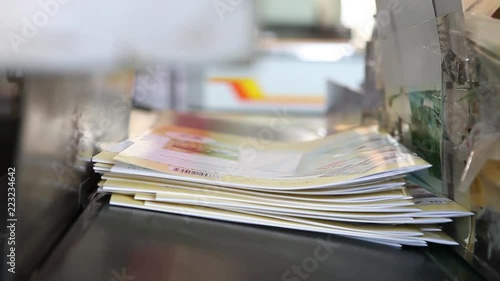 Video clip from a modern printing house. The worker takes fresh  magazines from the conveyor belt.