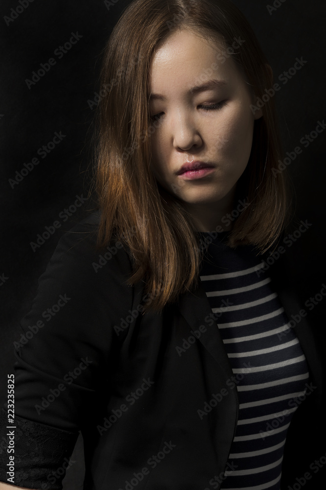 Beautiful young Mongolian woman on dark background. Fashion look.