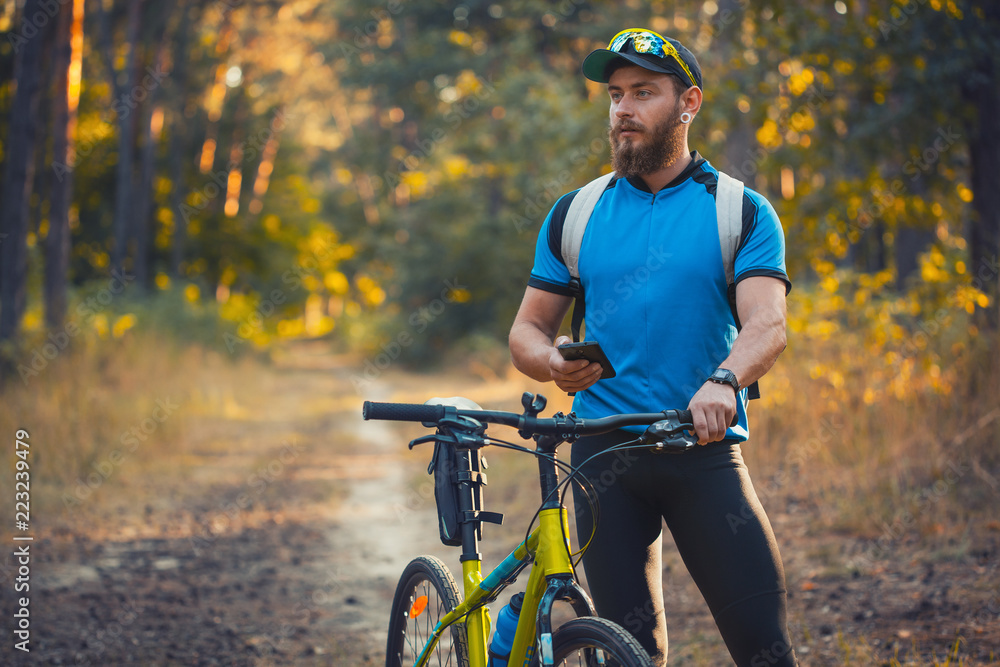Naklejka premium bearded man cyclist rides in the forest on a mountain bike.