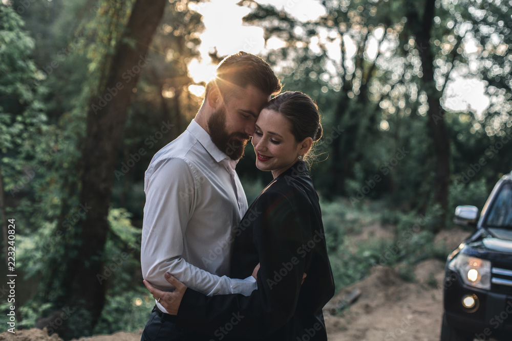 Obraz premium A young married couple came to the lake on a black car during sunset