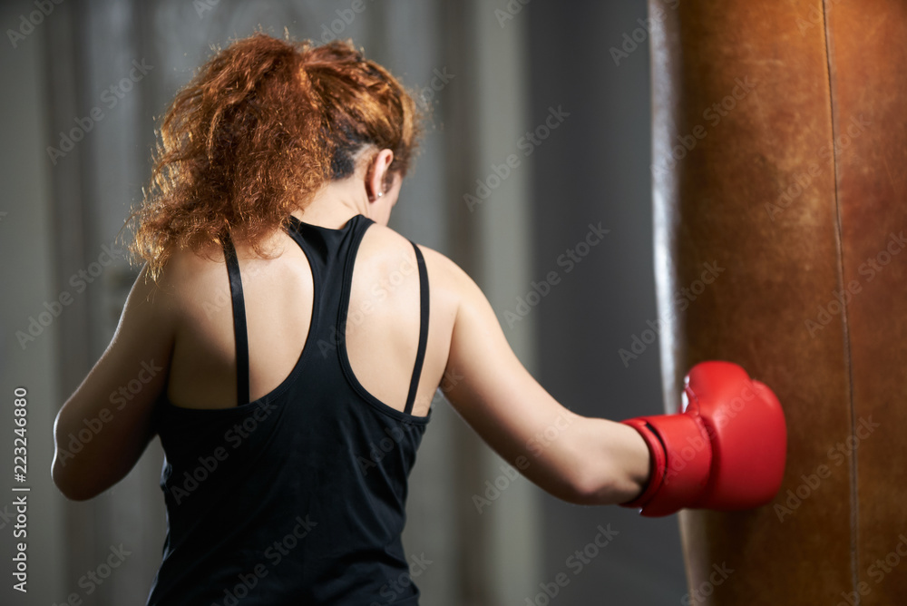 Sport woman wear boxing glove kick boxer in the gym. Crossfit fitness woman kick boxing with punching bag Sport woman wear boxing glove kick boxer in the gym. Crossfit fitness woman kick boxing with punching bag