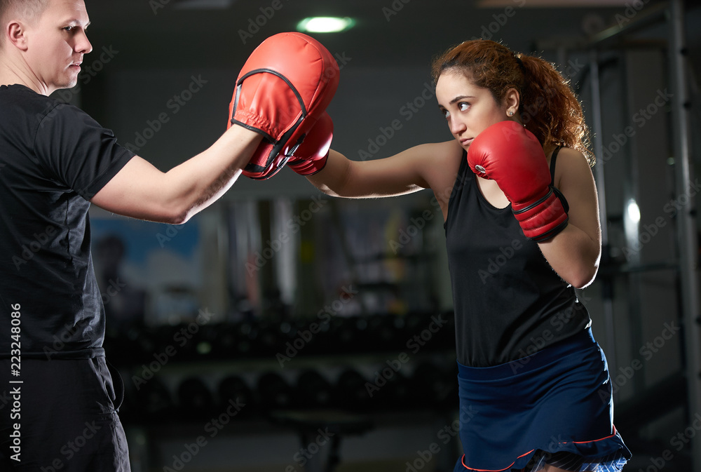 Young woman doing kickboxing training her coach. Woman fighter ready to throw a punch with teacher holding for boxing session Stock Photo | Adobe Stock