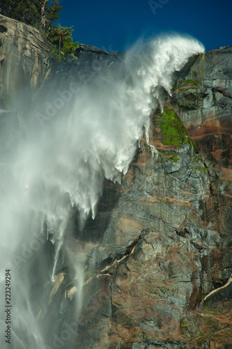 Water flows over the Bridal Veil Falls at Yosemite in June 2018. A shot of the movement of the water in the wind. Vertical image.