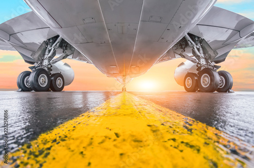 Modern passenger airplane parked airport with airplane parts jet engine wing landing gear sunset setting sun view air travel background. photo