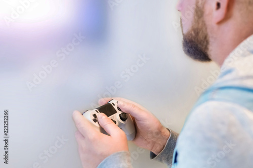 man with a beard playing a game console, rear view, copy space